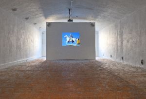 Vue de l’exposition *Coup d’éclat*, Fort du Bruissin, 2011. Sur l’image : Amelia Pica,*On education* , 2008, vidéo-projection, 8mm transférée sur DVD, 4’45’’. Photo : Blaise Adilon