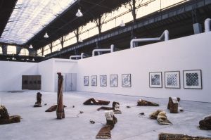 Exhibition view, *L’exposition de l’École du Magasin*, 1991. Front:   installation by Jårg Geismar. On the far left corner: installation by Michel Aubry. On the wall: series by Bernard Voïta.