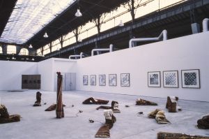 Vue de *L’exposition de l’École du Magasin*, 1991. Devant :   installation de Jårg Geismar. Au fond à gauche : installation de Michel Aubry. Sur le mur: série de Bernard Voïta.